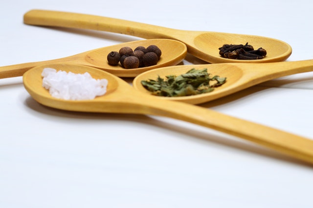salt, pepper and herbs in wooden spoons